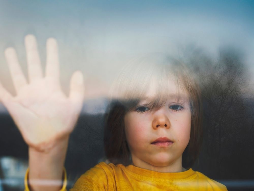 Enfant autiste posant sa main contre une vitre, illustrant la perception unique du monde et la neurodiversité.