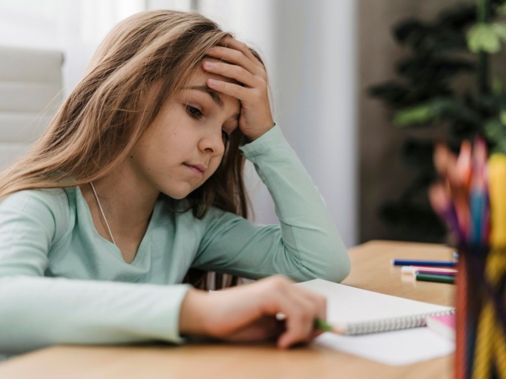 Jeune fille à son bureau illustrant les difficultés de concentration liées au TDAH et au TSA, accompagnée par les méthodes d'Harmonie Apprentissage à Thionville.