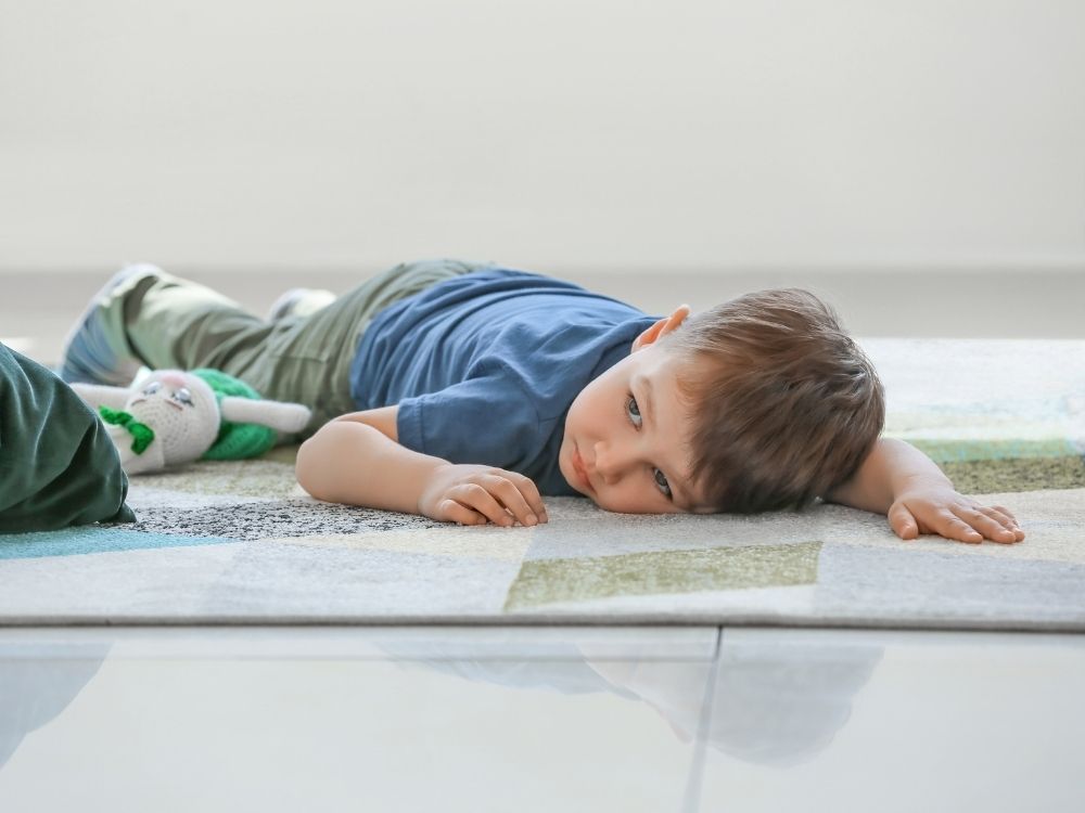 Jeune enfant allongé au sol, dans son monde.