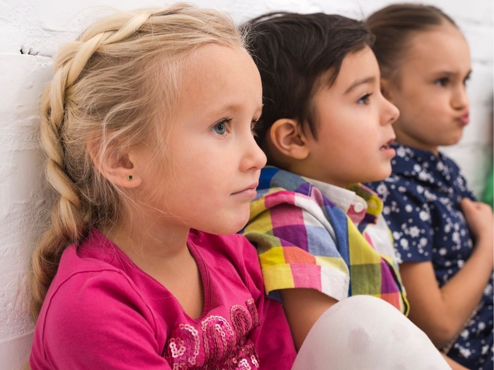 Trois enfants assis côte à côte, illustrant l'intégration sociale et l'autisme "invisible"