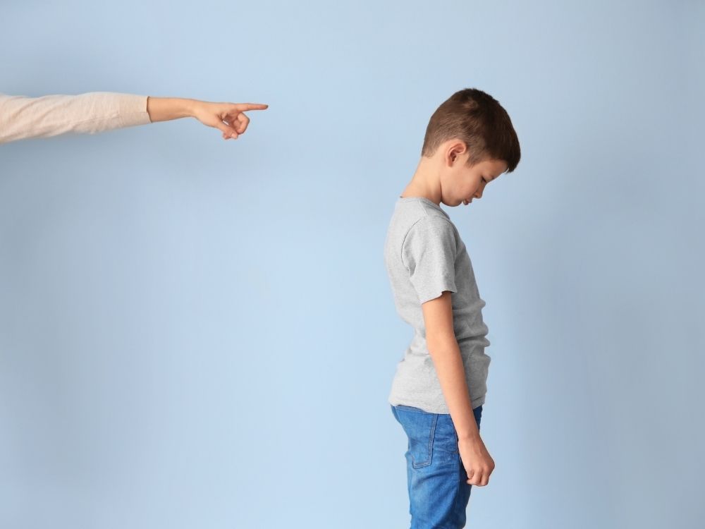Enfant tête baissée et main d'adulte pointant du doigt symbolisant la punition