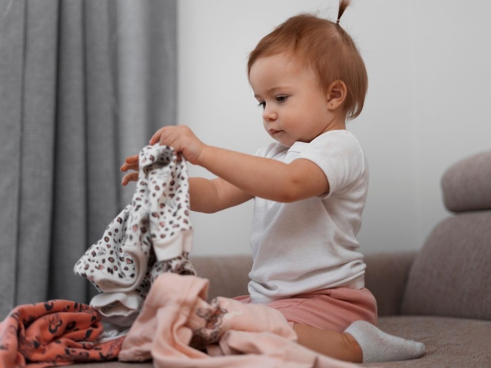 Jeune enfant apprenant à s'habiller seule pour développer son autonomie au quotidien.