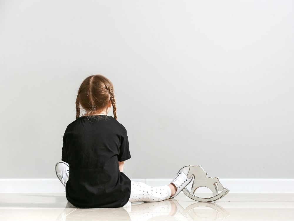 Enfant de dos sur un sol clair, illustrant la sensibilité sensorielle et l'accompagnement d'un public autiste non verbal