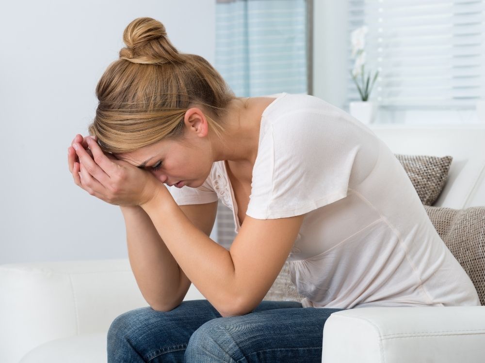 Femme assise se tenant la tête, exprimant la fatigue et le besoin d'un suivi adultes